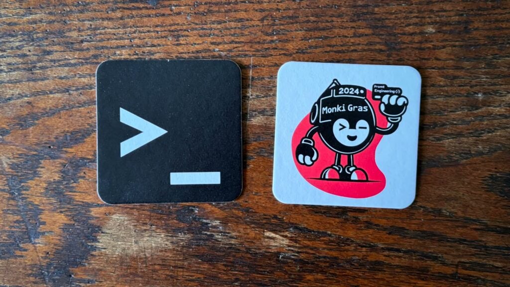 image of two beer mats, one a simple image like a command prompt, the other a logo of a funny little guy created by an AI to illustrate the monkigras event 