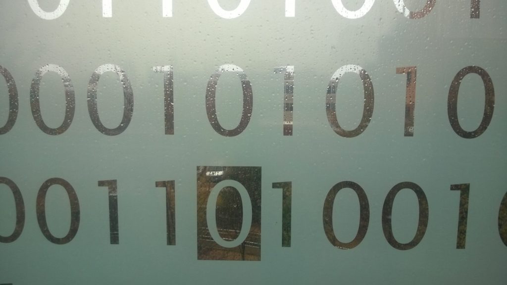 A pane of frosted glass etched with 1s and 0s.