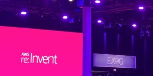 A sign that reads "Expo" is displayed above a door. To the left is a screen projecting text that reads "AWS re:Invent"