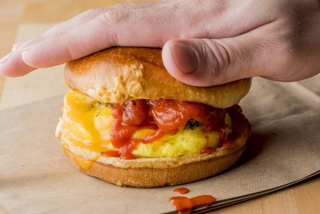 hand smooshing a breakfast sandwich