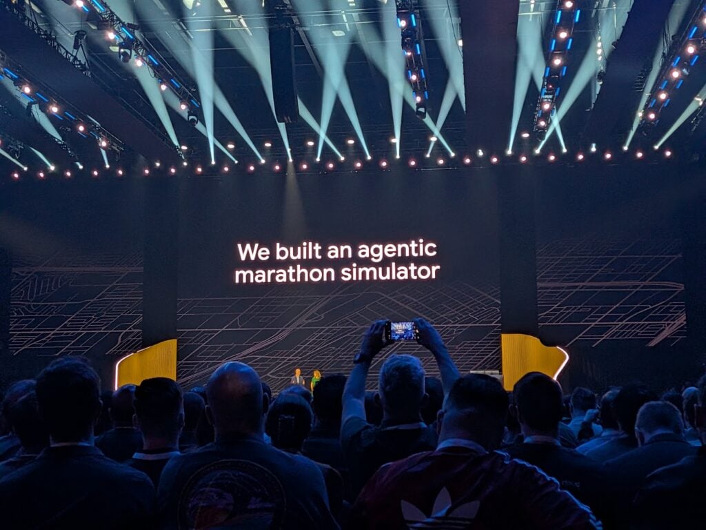 view of the Developer Keynote at Google Cloud Next 2026. Spotlights are flicking across the room and the text on the slide reads simply: "We built an agentic marathon simulator".