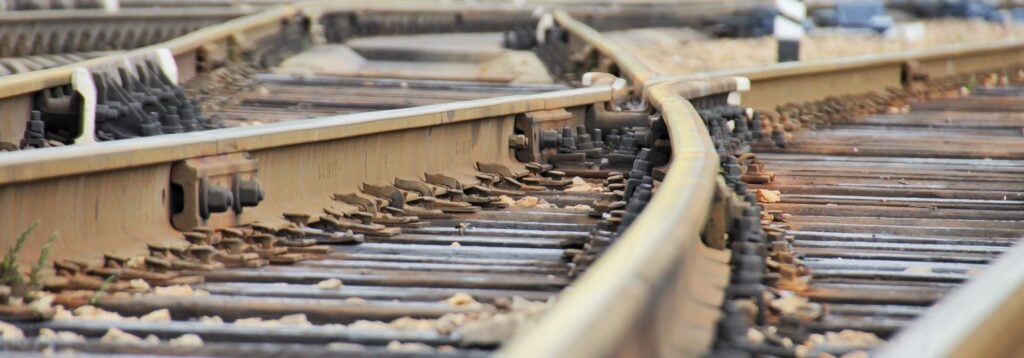 Railroad rails at a small station, fork, arrows, mechanical elements, wide view.