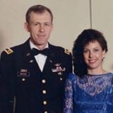 A man in a dress Army uniform stands next to a woman in a blue evening gown.