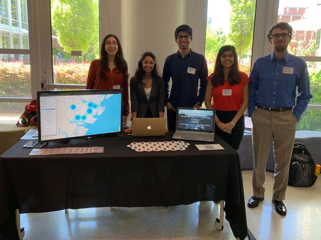 Team 8352 and their project on Visualizing Data from Sea Level Sensors. Table display includes multiple monitors demonstrating the app; a handout explaining the app; and artfully arranged stickers.