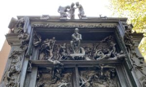 Image of the top of Rodin's sculpture "The Gates to Hell" comprising versions of his other well-known works (e.g. "The Thinker") placed around a large set of doors.