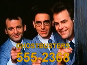 Image of Bill Murray, Harold Ramis, and Dan Akroyd from the 1984 film Ghostbusters. All three point at the viewer as part of an in-film commercial; the text and fictitious phone number "Ghostbusters 555-2368" scroll across the bottom of the screen.