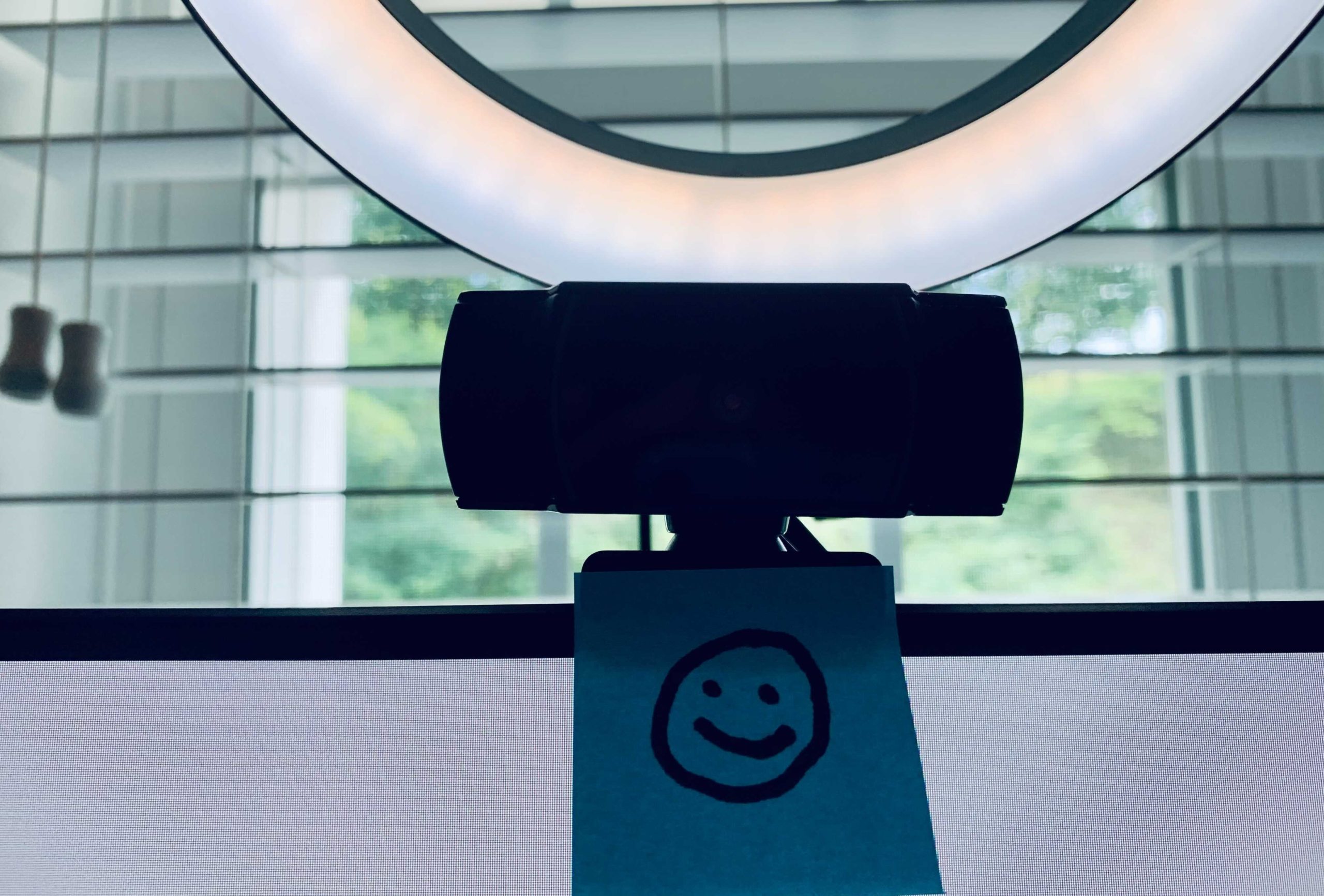 photo of a web cam with a sticky note containing a smiley face just below it
